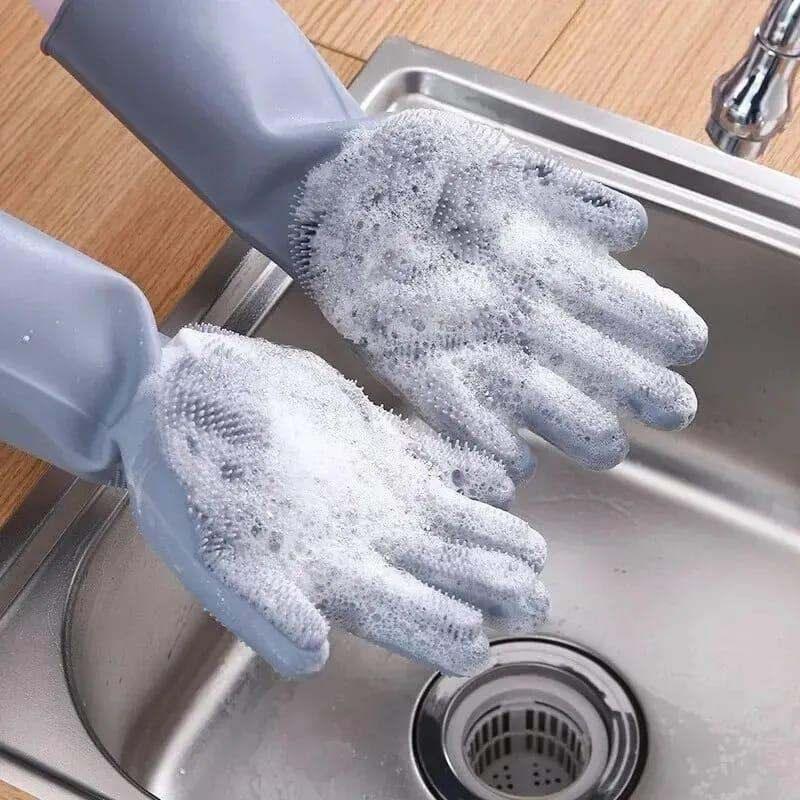 Gray automatic dish washing gloves with built-in silicone bristles, covered in soap bubbles over a kitchen sink, designed for effortless cleaning and hand protection